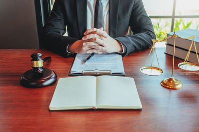 Midsection of man reading book on table