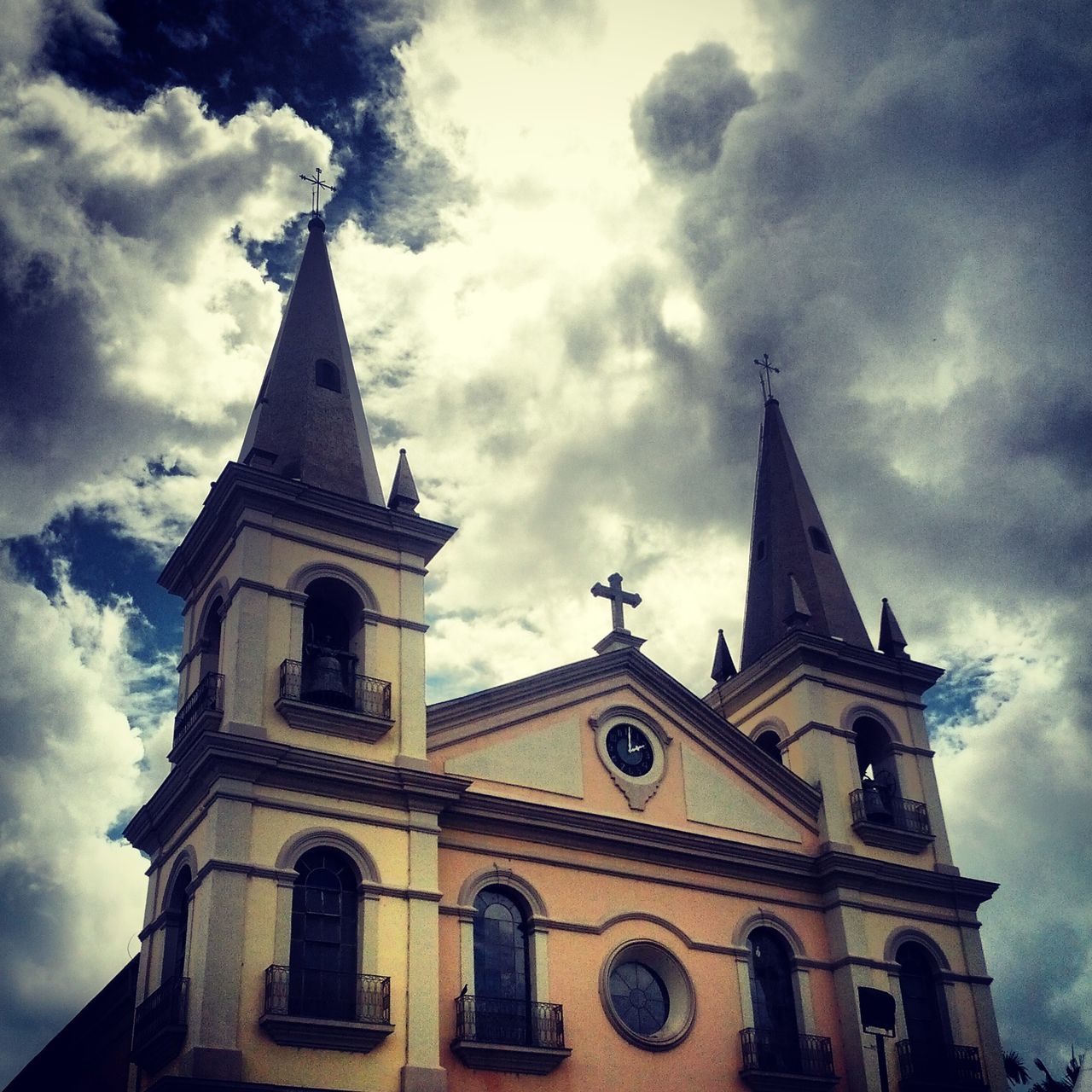 religion, church, place of worship, architecture, spirituality, building exterior, low angle view, built structure, sky, cathedral, cross, cloud - sky, cloudy, steeple, cloud, clock tower, tower, high section