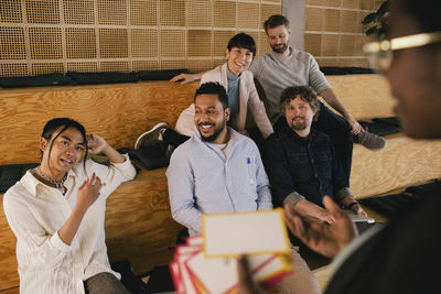 Multiracial colleagues discussing with businesswoman holding placard during meeting in office