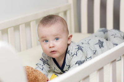 Portrait of cute baby boy relaxing in crib at home