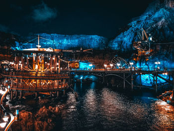 Illuminated bridge over river against sky at night