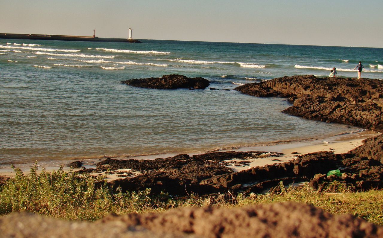 sea, horizon over water, water, beach, tranquil scene, shore, tranquility, scenics, beauty in nature, clear sky, nature, sand, coastline, idyllic, sky, grass, wave, blue, remote, plant