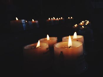 Close-up of lit tea light candles in dark room