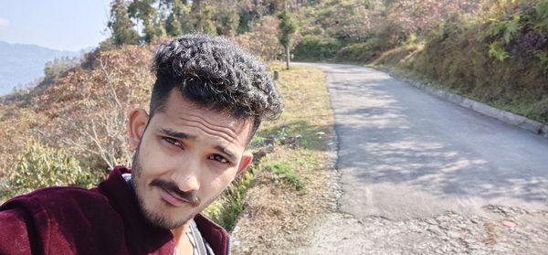 Portrait of young man looking away while road