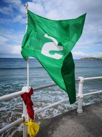 Rear view of flag on boat in sea against sky