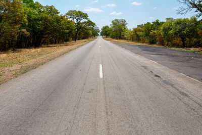 Empty road amidst trees against sky