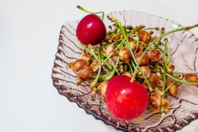 Red ripe cherries and eaten cherry seeds on a plate.