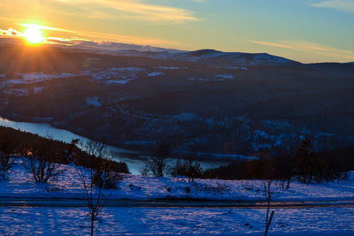 Scenic view of snow covered mountains against sky at sunset