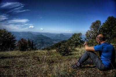 Man sitting on land against sky