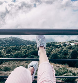 Low section of woman on railing against sky