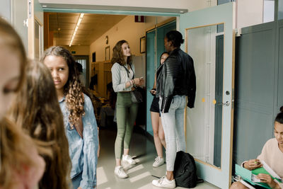 Junior high students standing by door in school corridor