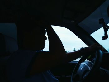 Low section of silhouette man in car