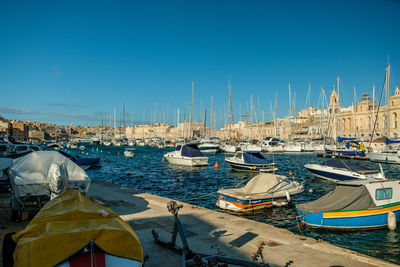 Boats in harbor against clear blue sky