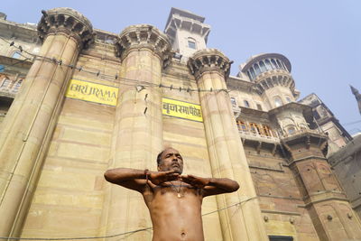 Low angle view of man meditating against historic building