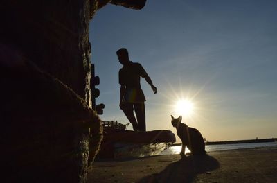 Silhouette men on land against sky during sunset
