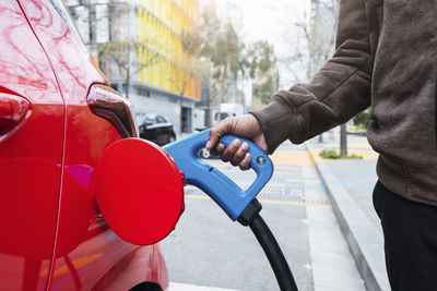 Hand of man charging car at electric station