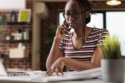 Young woman using phone while sitting on table