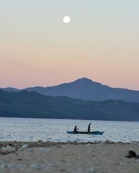 People sailing boat in sea against sky