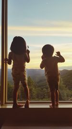 Full length of father and son standing on window