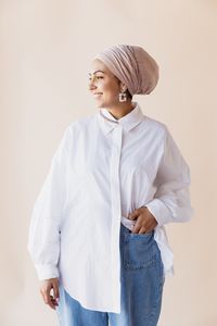 Woman looking away while standing against white background