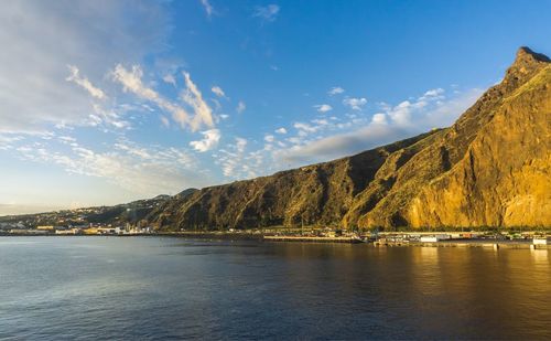 Scenic view of river by mountains against sky