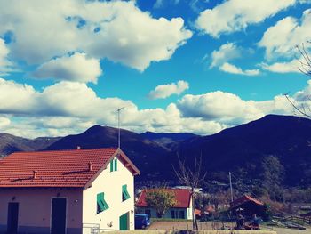 Houses in town by mountains against sky