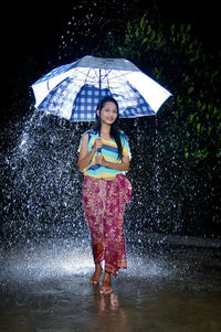 Full length portrait of woman standing in rain