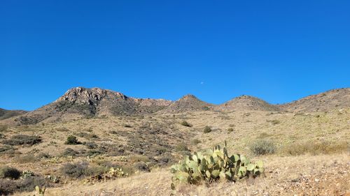 Scenic view of arid landscape against clear blue sky