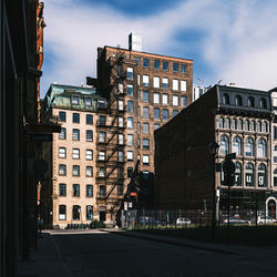 Buildings by road against sky in city