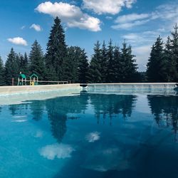 Swimming pool by lake against sky