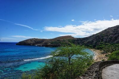 Scenic view of sea and mountains against blue sky