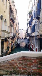 Canal amidst buildings against sky