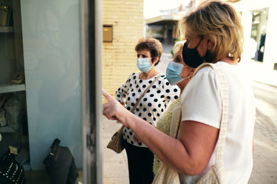 Mature women looking at a window and pointing at the bag