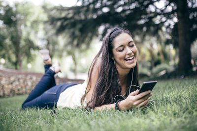 Smiling woman listening music while sitting in park