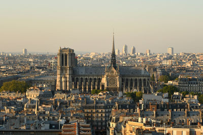 Notre dame de paris amidst buildings in city against clear sky