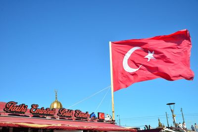 Low angle view of american flag against clear blue sky