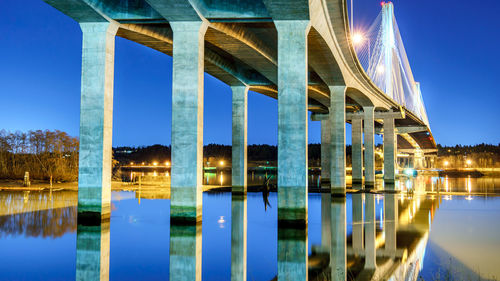 Reflection of bridge on river against sky at night