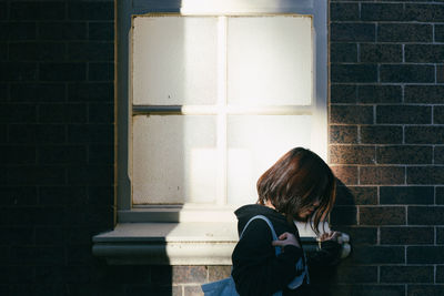 Rear view of woman standing against wall