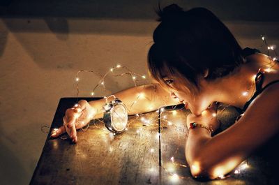 Woman with illuminated lights and clock on table