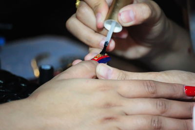 Cropped hand of beautician applying nail polish to woman