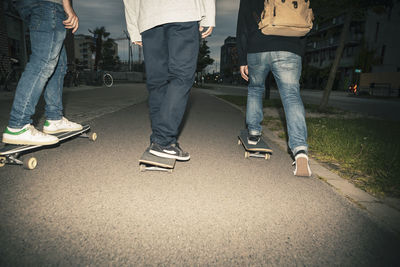 Low section of male friend skateboarding during dusk