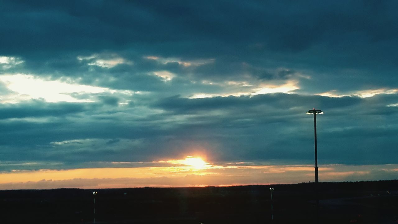 sunset, silhouette, sky, cloud - sky, scenics, beauty in nature, sun, tranquil scene, landscape, tranquility, nature, orange color, cloud, idyllic, sunlight, sunbeam, cloudy, dramatic sky, street light, field