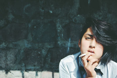 Close-up of young woman standing against wall