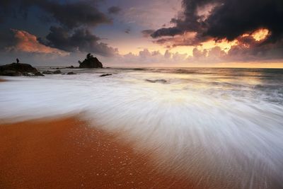 Scenic view of beach against dramatic sky