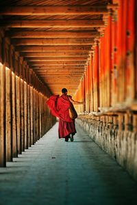 Rear view of monk walking at temple corridor