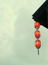 Low angle view of illuminated lanterns hanging from roof against sky