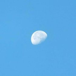 Low angle view of moon against clear blue sky