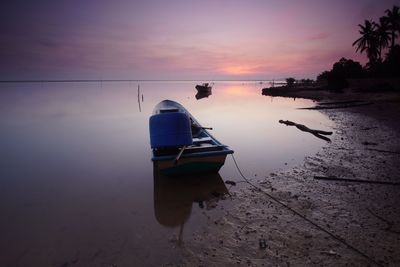 Boat moored on sea against sky during sunset