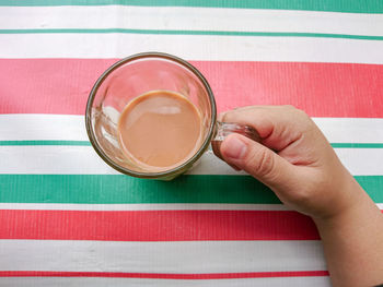 Close-up of hand holding coffee cup on table