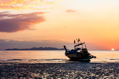 Boat moored in sea against sky during sunset